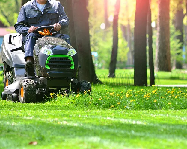 Homme tondant la pelouse d'un parc avec une tondeuse autoportée à Brûlon dans la Sarthe 72