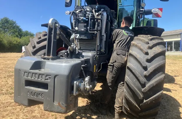 Un homme répare un tracteur vert Claas de 900 kg dans un champ ensoleillé à Brûlon dans la Sarthe 72