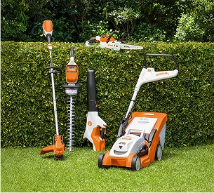 Un ensemble d'outils de jardinage sans fil STIHL orange et blanc sur une pelouse verte à Brûlon dans la Sarthe 72
