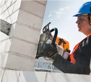 Un homme en tenue de sécurité coupe une brique avec une tronçonneuse à béton à Brûlon dans la Sarthe 72